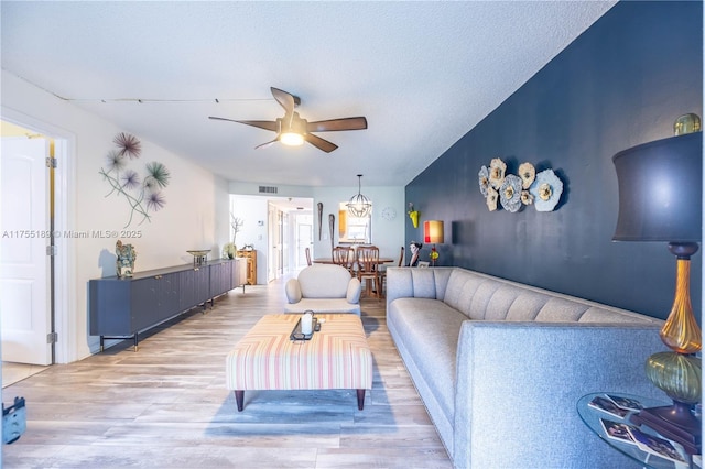 living area with visible vents, a textured ceiling, a ceiling fan, and wood finished floors