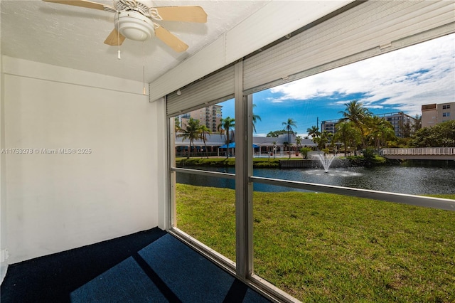 unfurnished sunroom featuring a water view and ceiling fan