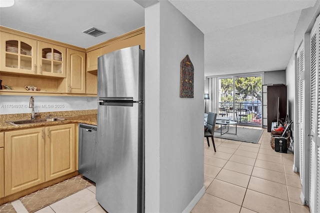 kitchen featuring light tile patterned floors, stainless steel appliances, visible vents, light brown cabinetry, and a sink