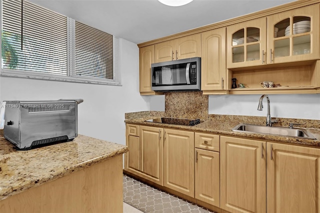 kitchen featuring black electric cooktop, stainless steel microwave, a sink, and light brown cabinetry