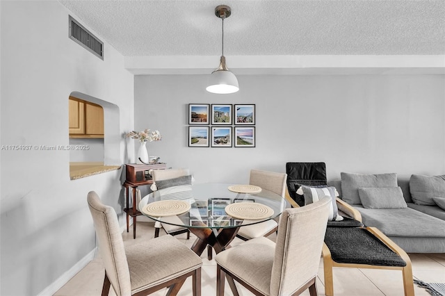 dining area featuring visible vents, a textured ceiling, and light tile patterned flooring