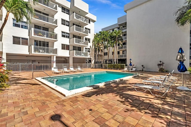 community pool with a patio area and fence