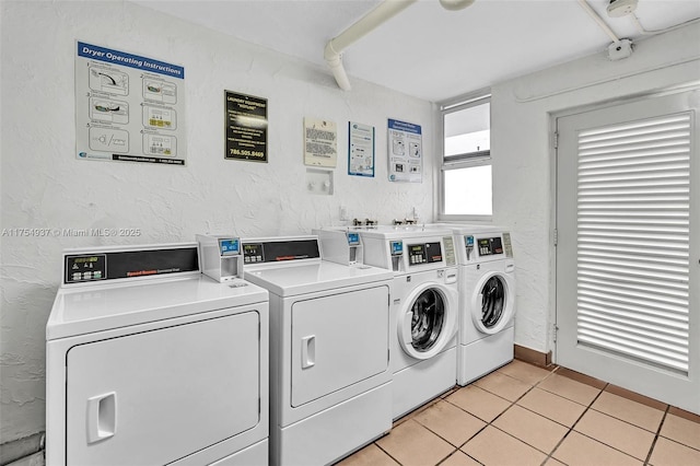 community laundry room featuring light tile patterned flooring, washer and clothes dryer, and a textured wall