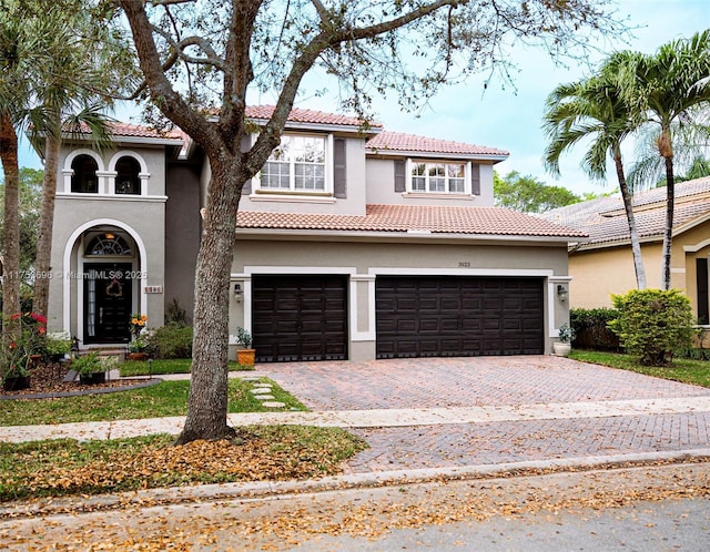 mediterranean / spanish-style house featuring stucco siding, a tile roof, and decorative driveway