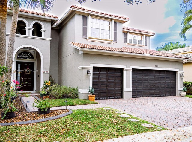 mediterranean / spanish-style home featuring stucco siding, decorative driveway, and a tiled roof