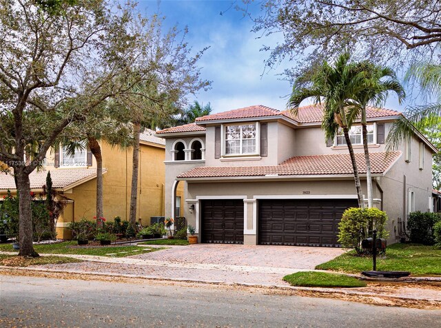 mediterranean / spanish-style house featuring stucco siding, a tiled roof, and decorative driveway