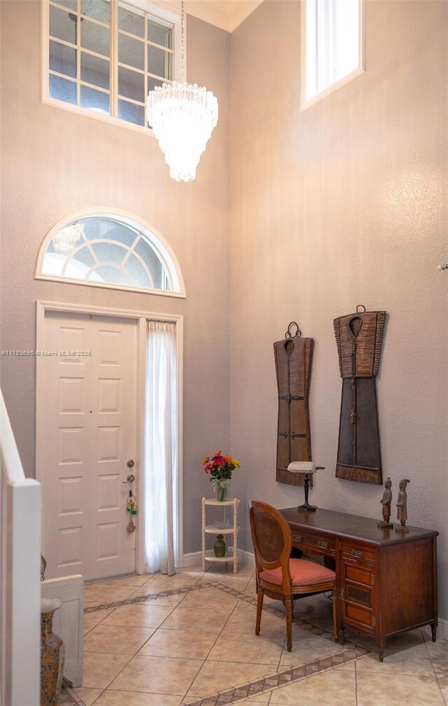 foyer with tile patterned flooring, a towering ceiling, and a chandelier