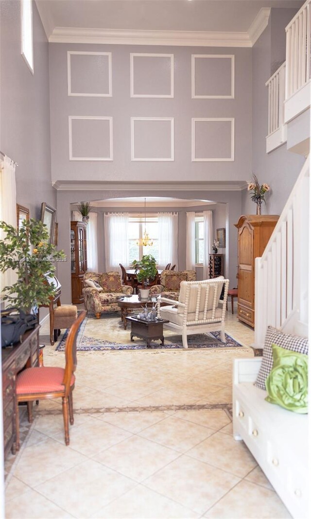 living room with crown molding, stairway, light tile patterned flooring, and a towering ceiling