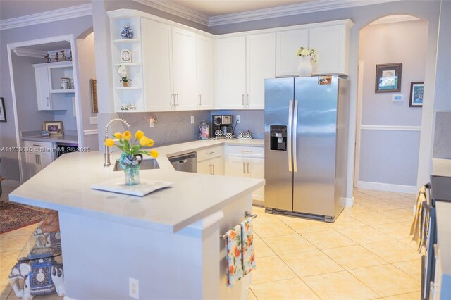 kitchen featuring ornamental molding, open shelves, arched walkways, appliances with stainless steel finishes, and a peninsula