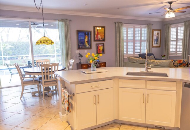 kitchen with crown molding, dishwasher, light countertops, light tile patterned floors, and a sink