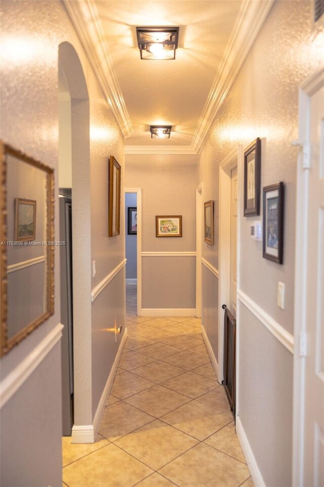 corridor featuring light tile patterned floors, arched walkways, track lighting, and crown molding