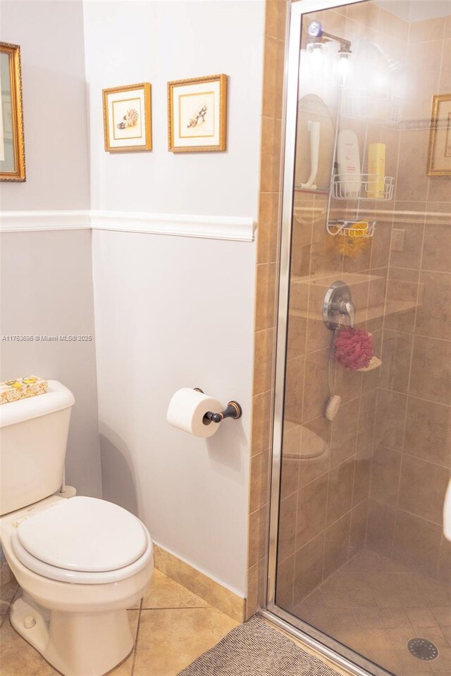 bathroom with tile patterned flooring, toilet, and a stall shower