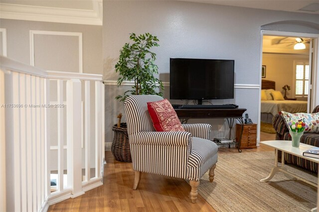 living room featuring a ceiling fan, crown molding, wood finished floors, and arched walkways