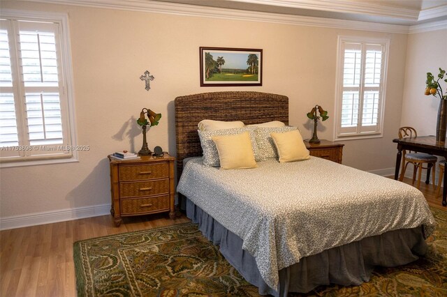 bedroom with baseboards, wood finished floors, and crown molding