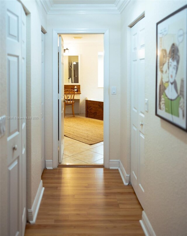 hall featuring baseboards, light wood-style floors, and ornamental molding