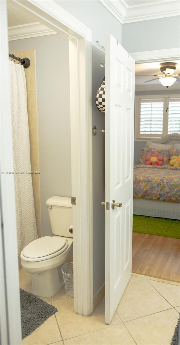 ensuite bathroom with tile patterned floors, toilet, ensuite bath, and ornamental molding