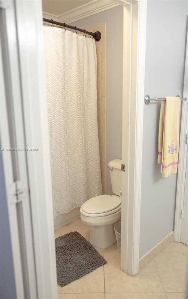 full bath with tile patterned flooring, toilet, crown molding, and baseboards