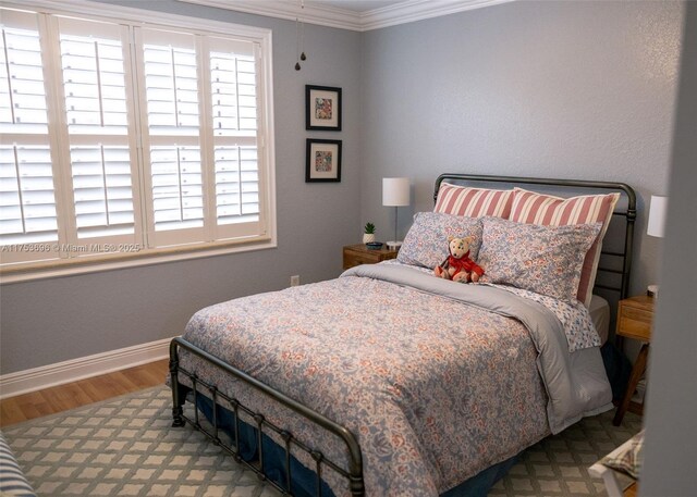 bedroom with crown molding, baseboards, and wood finished floors