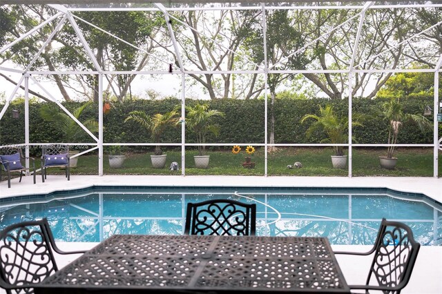 outdoor pool with glass enclosure and a patio