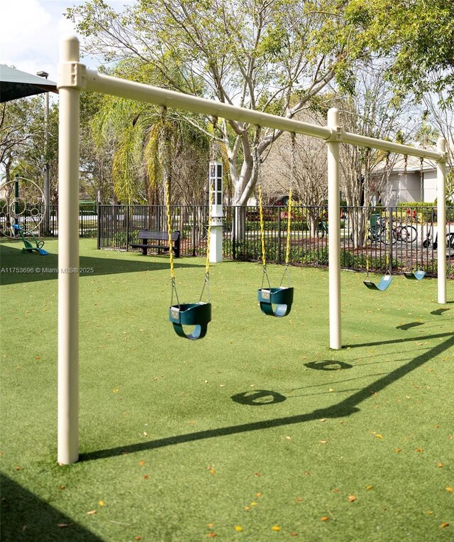 view of home's community with playground community, a lawn, and fence