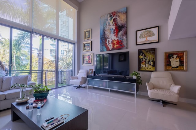 living area featuring a towering ceiling, tile patterned flooring, and baseboards