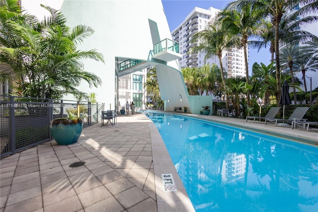 community pool with a patio area and fence