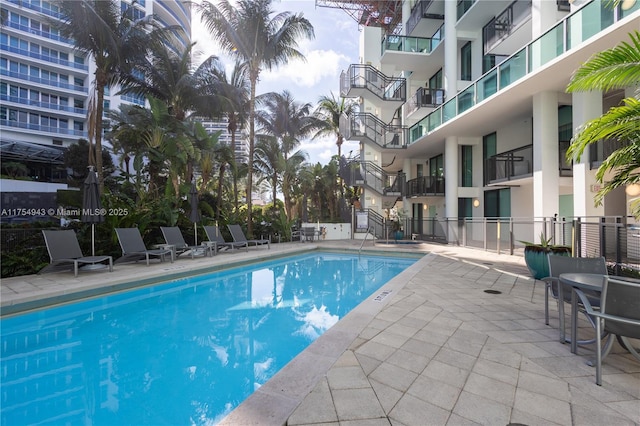 pool with a patio area and fence