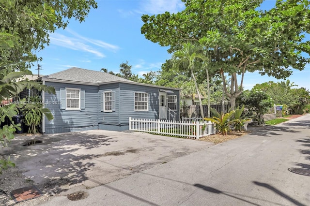 view of front of home with a shingled roof and fence