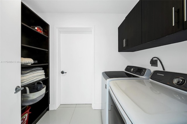 clothes washing area with light tile patterned flooring, cabinet space, and washer and dryer