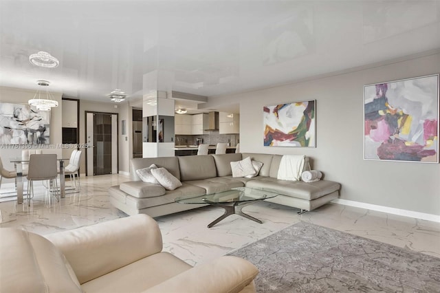 living room featuring marble finish floor, an inviting chandelier, and baseboards