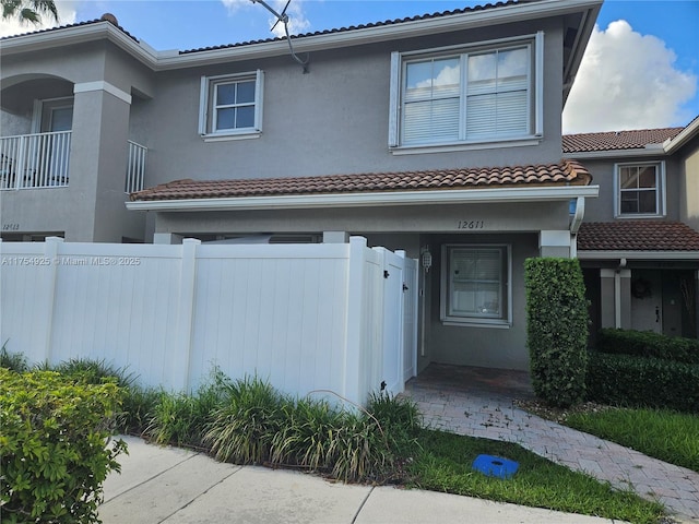 view of front of house featuring a fenced front yard, a tiled roof, and stucco siding