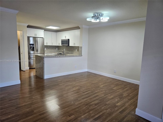 kitchen featuring crown molding, decorative backsplash, appliances with stainless steel finishes, white cabinets, and a sink