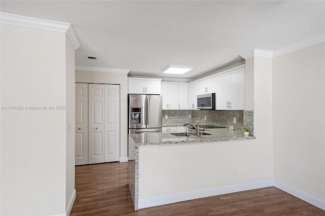 12611 SW 54th Ct Unit 12611, Miramar, FL 33027 - kitchen with appliances with stainless steel finishes, backsplash, ornamental molding, dark wood finished floors, and white cabinets