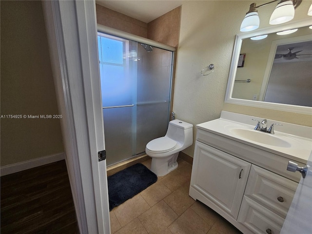 full bath featuring toilet, vanity, baseboards, tile patterned floors, and a stall shower