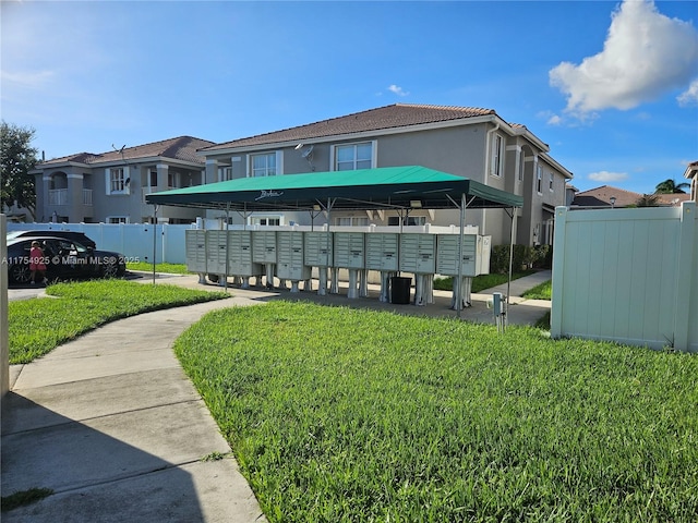 view of home's community featuring a lawn, a residential view, fence, and mail area