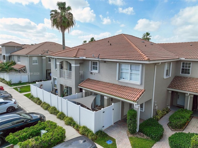 view of front of home featuring a tiled roof, fence private yard, a gate, and stucco siding