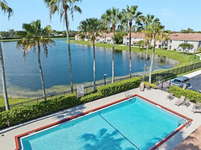 pool featuring a residential view, a water view, fence, and a patio