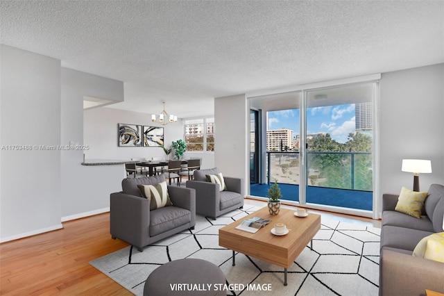 living area with baseboards, expansive windows, a textured ceiling, light wood-style floors, and a notable chandelier