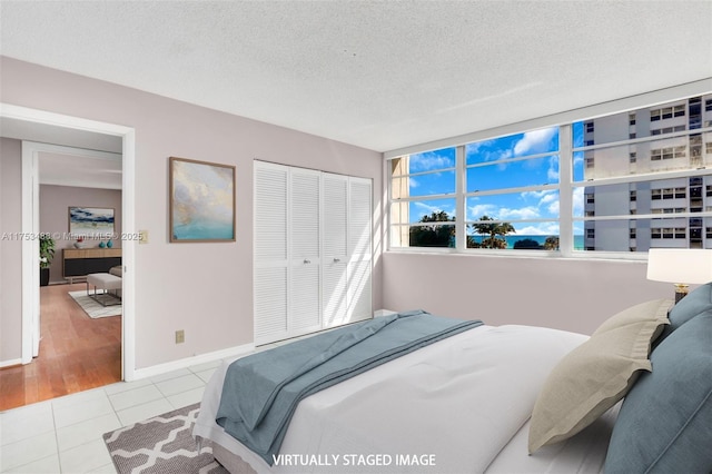 tiled bedroom with a closet, baseboards, and a textured ceiling