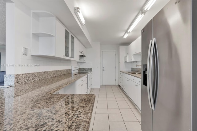 kitchen with white cabinets, stainless steel fridge, range with electric cooktop, and open shelves