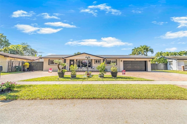 ranch-style house with an attached garage, fence, concrete driveway, and a front yard