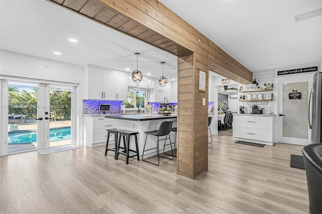 kitchen with a healthy amount of sunlight, white cabinets, a breakfast bar, and decorative backsplash