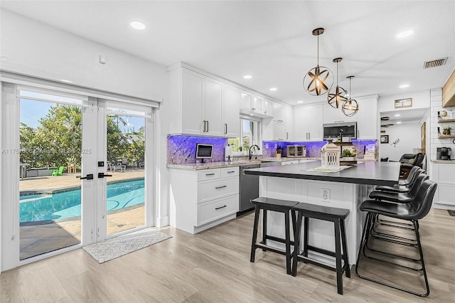 kitchen with french doors, a breakfast bar area, stainless steel appliances, visible vents, and backsplash