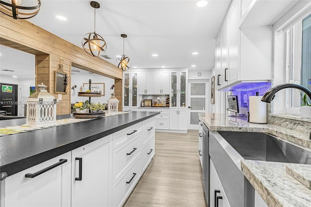 kitchen featuring recessed lighting, hanging light fixtures, light wood-style floors, white cabinetry, and a sink