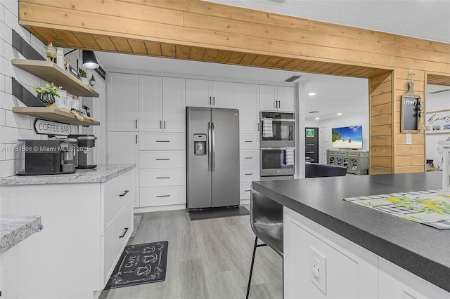 kitchen with light wood finished floors, open shelves, appliances with stainless steel finishes, and white cabinetry