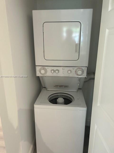 clothes washing area with stacked washer and dryer and laundry area