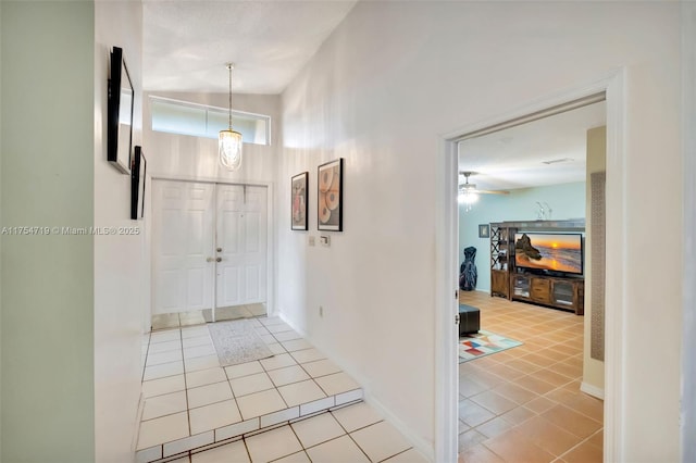 foyer entrance with baseboards, a ceiling fan, and light tile patterned flooring