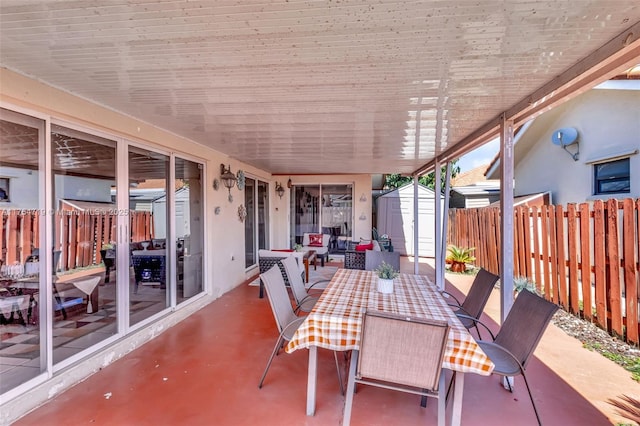 view of patio / terrace with outdoor dining area, a fenced backyard, an outdoor structure, and a shed