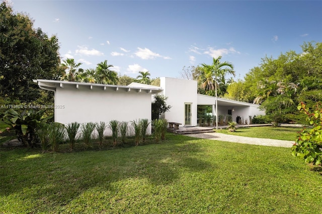 back of property with a yard and stucco siding