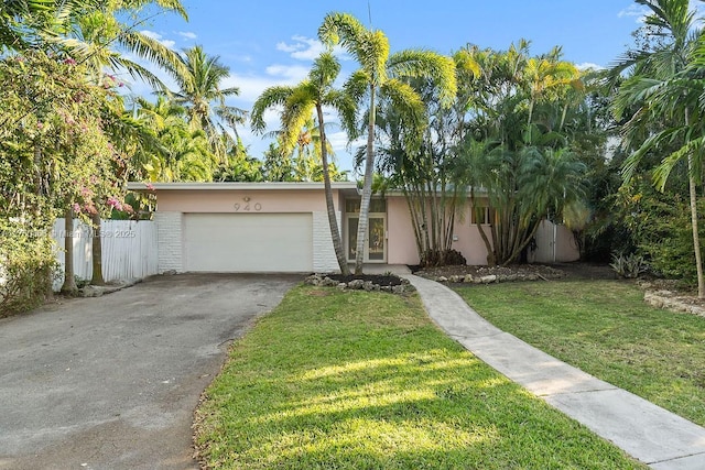 view of front of home with a garage, fence, driveway, stucco siding, and a front yard